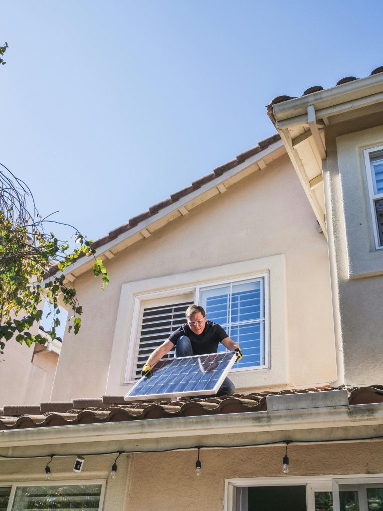 pexels-photo-9875407-9875407 A worker installs a solar panel on a residential rooftop, showcasing renewable energy technology.